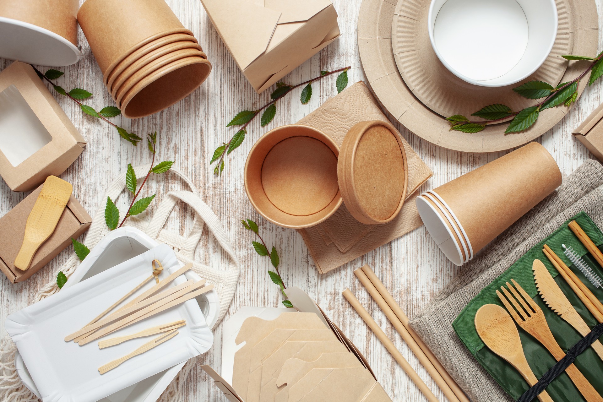 Eco craft paper tableware. Paper cups, dishes, bag, fast food containers and wooden cutlery on pink background. Recycling or zero waste concept. Top view. Copy space