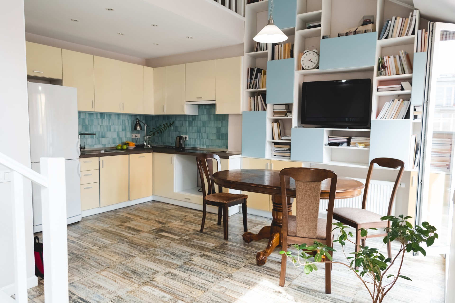 modern kitchen with wooden chairs and table near green plant